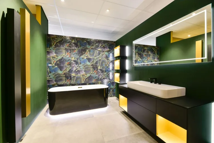 Badkamer met groene wanden, een donker bad en uitgesproken wandtegels.
