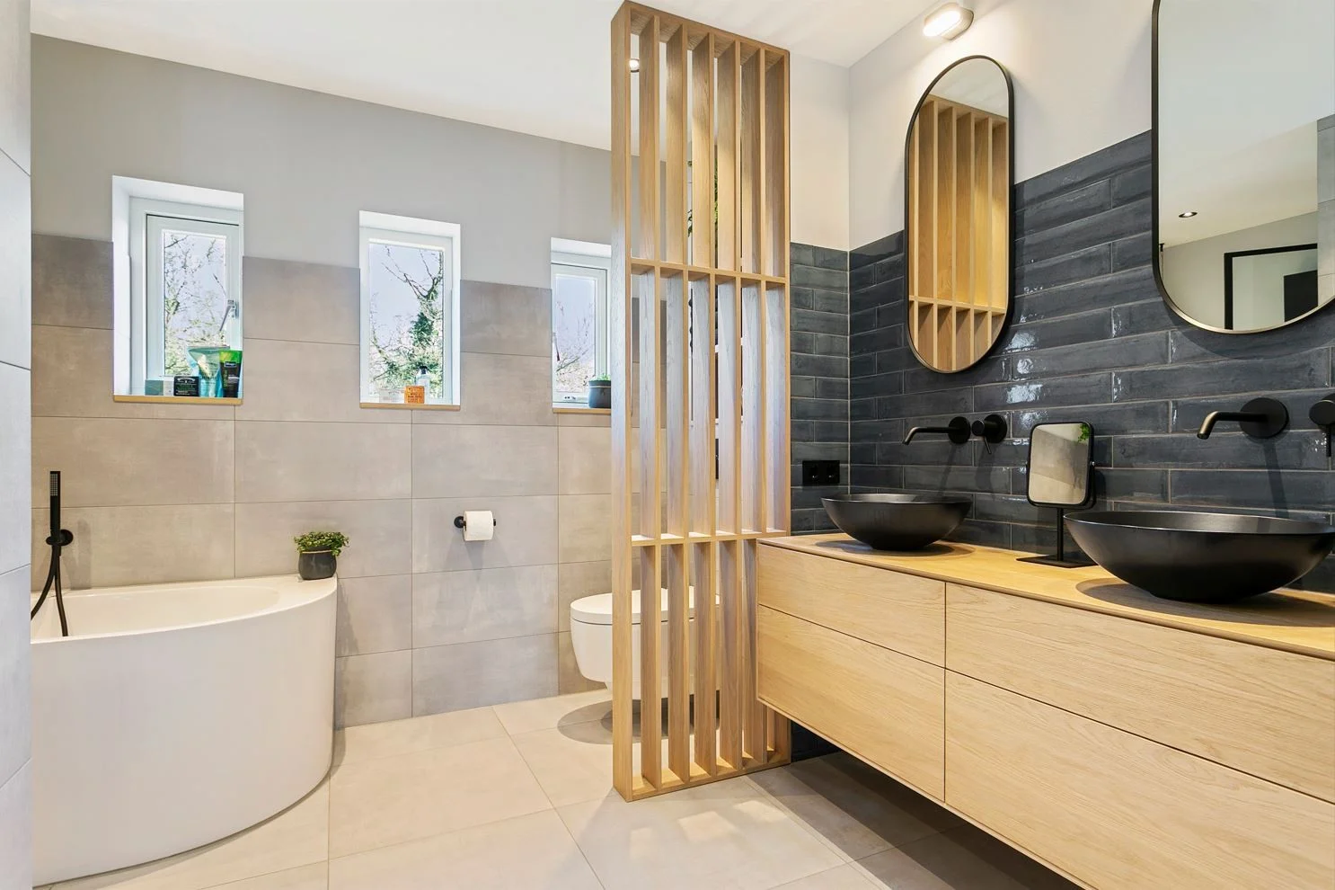 Lichte badkamer met houten meubel en houten verticale latten naast het bad.