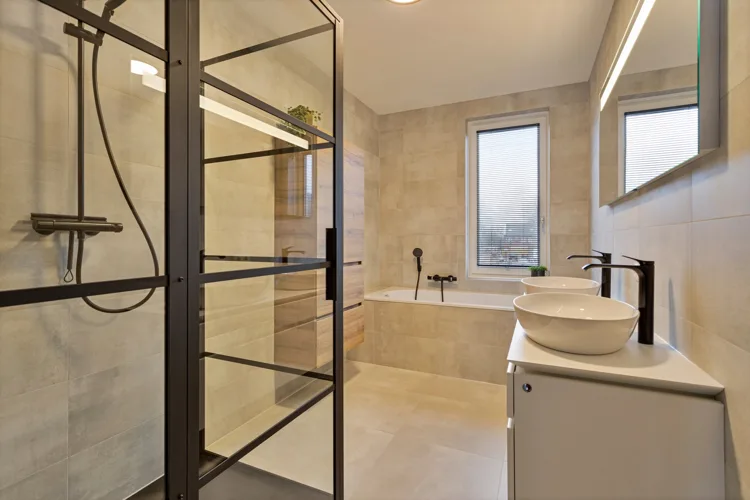 Compacte badkamer met zwarte doucheprofielen en een ronde waskom.
