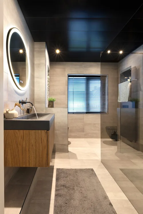Doorkijk in een smalle badkamer met een donkere douchewand.