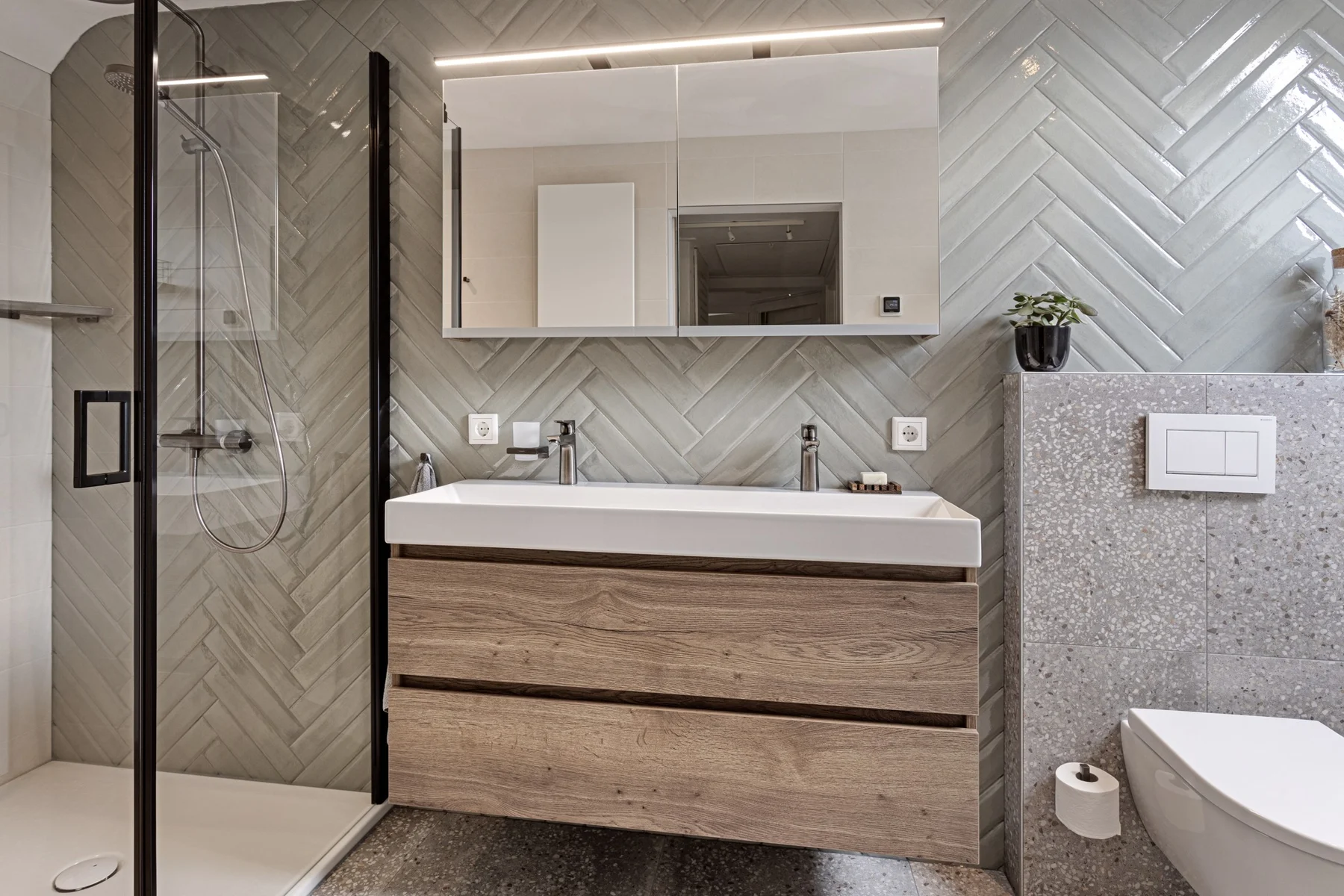 Compacte badkamer met houten meubel en glazen inloopdouche.