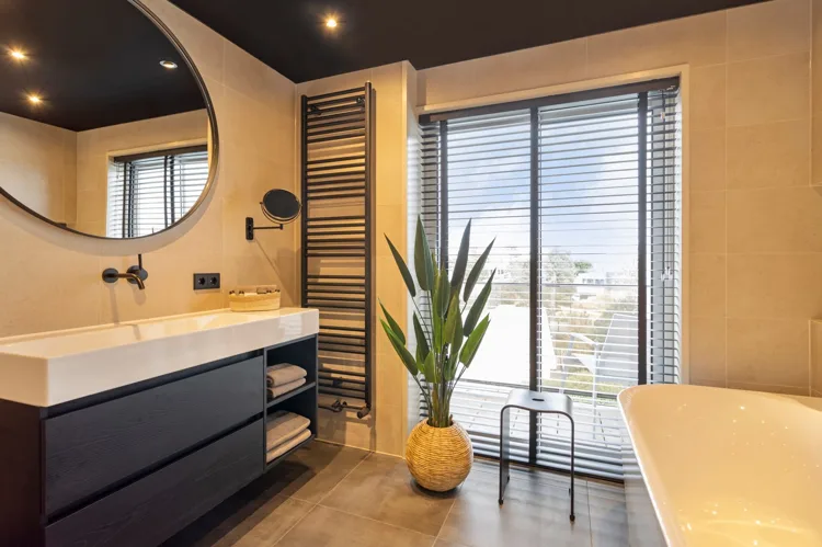 Warme badkamer met beige wandtegels en een zwart wastafelmeubel.