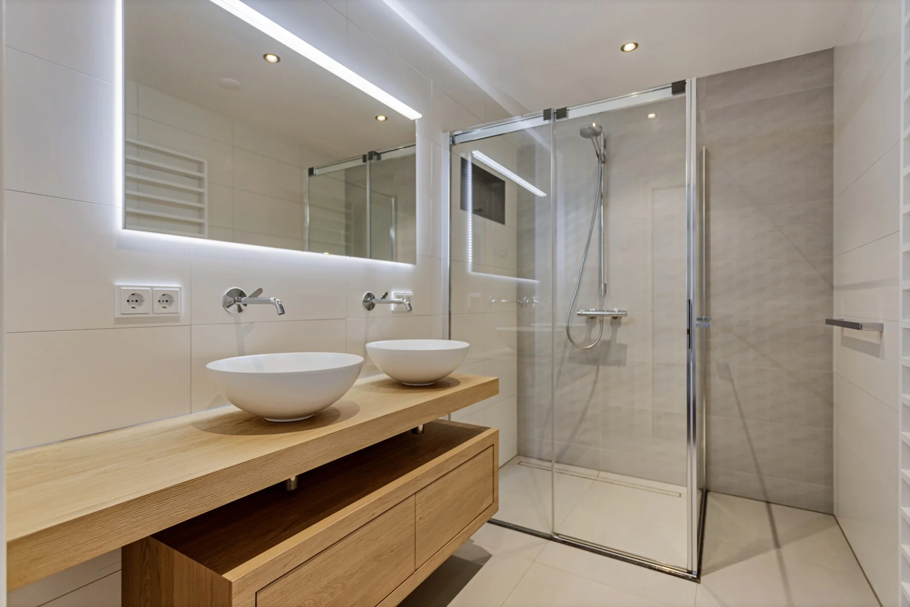 Lichte badkamer met een dubbele waskom en een ruime douche.