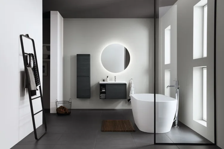 Badkamer met vrijstaand bad en een ronde spiegel.
